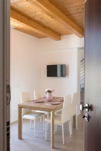 ein Esszimmer mit einem Holztisch und weißen Stühlen in der Unterkunft Dimora Caprera - Appartamenti in Falconara Marittima