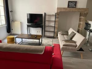 a living room with a red couch and a tv at Sand Home in Le Puy-en-Velay