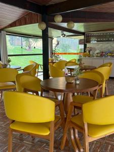 a restaurant with yellow chairs and a wooden table at Pousada Dona Carmita in Brumadinho