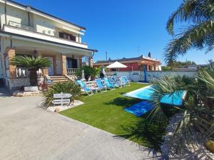 a house with a yard with chairs and a swimming pool at Alloggio del Pescatore e Alloggio del Marinaio con Piscina Palestra Jacuzzi Sauna - All Inclusive in Anzio