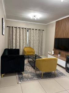 a living room with a black couch and yellow chairs at Dainfern Luxe Living - 2 Bed in Fourways