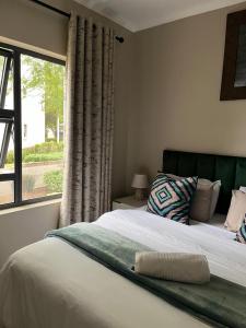 a bedroom with a large bed with a window at Dainfern Luxe Living - 2 Bed in Fourways