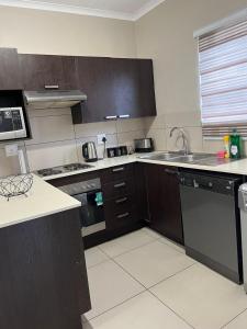 a kitchen with a sink and a stove top oven at Dainfern Luxe Living - 2 Bed in Fourways