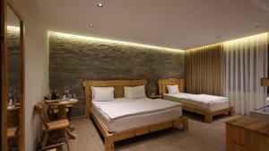 a bedroom with two beds and a brick wall at Perla e Tomorrit EZ in Ujanik