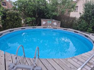 a large blue swimming pool on a wooden deck at Le figuier in Benayes