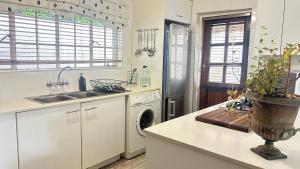 a white kitchen with a sink and a dishwasher at Artzys Cottage 1km to Olivedale Clinic in Northriding +36 photos