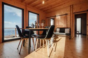 a dining room with a table and chairs and windows at Recanto Terra Alta in São Roque do Pico