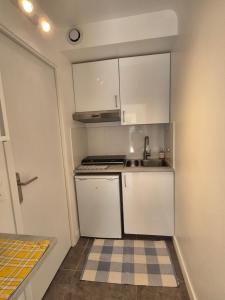 a small kitchen with white cabinets and a sink at Studio Neuf et indépendant in LʼÉtang-la-Ville +6 photos