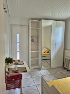 a living room with a table and a room with a bed at Studio Neuf et indépendant in LʼÉtang-la-Ville