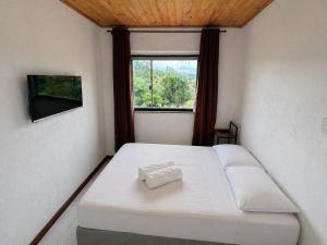 a bedroom with a white bed and a window at Casa com 2 suítes em Lavras Novas in Ouro Preto