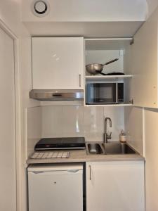 a kitchen with a sink and a microwave at Studio Neuf et indépendant in LʼÉtang-la-Ville