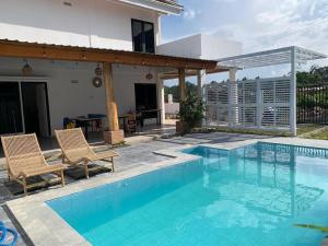 a swimming pool with two chairs and a house at villa Elfame Lokon in Tomohon