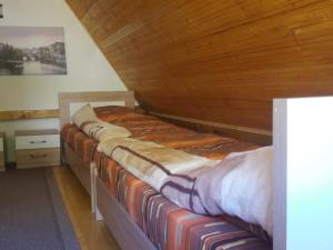 two beds in a room with a wooden ceiling at Vikendica Ivanović in Prisoja