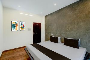 a bedroom with a large white bed with black pillows at Hotel O Dream Vegas in Hyderabad