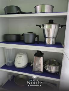 a kitchen shelf with pots and pans and a blender at SUITES SANTA FÉcg A5 in Campo Grande