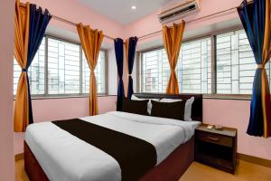 a bedroom with a large bed and windows at Hotel O Newtown worldstay in Thākurdwari