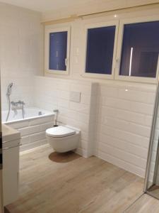 a white bathroom with a toilet and a bath tub at Appartement 2 chambres avec balcon terrasse in Villars-sur-Glâne +4 photos