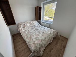 a small bedroom with a bed with a comforter and a window at Tatrabyt in Bánovce nad Bebravou