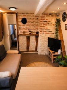 a living room with a couch and a tv at Le logis Bressan-cosy-clim in Coligny