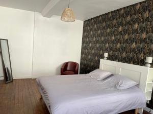 a bedroom with a white bed and a chair at Maison de ville in Évron +4 photos