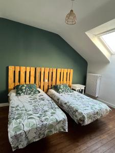 a bedroom with two beds and a green wall at Maison de ville in Évron
