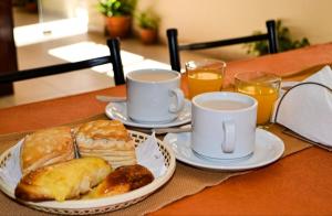 two cups of coffee and plates of pastries on a table at Hotel Ke Kuul in Salta
