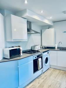 a kitchen with a microwave and a washer and dryer at Folkestone Harbour Modern Comfortable Flat F3 in Folkestone