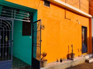 an orange building with a green door and potted plants at Auro Delight - Near Auroville in Pondicherry in Villupuram