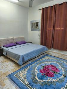 a bedroom with a bed and a rug with flowers on it at شقة مفروشة بمدينة نزوى in Fulūj Sayghah