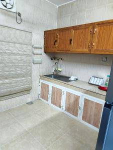 a kitchen with wooden cabinets and a sink at شقة مفروشة بمدينة نزوى in Fulūj Sayghah