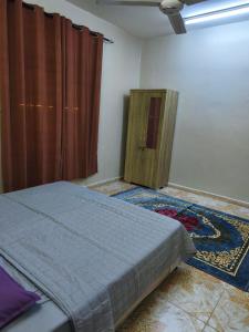 a bedroom with a bed and a wooden cabinet at شقة مفروشة بمدينة نزوى in Fulūj Sayghah +2 photos