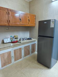 a kitchen with a refrigerator and wooden cabinets at شقة مفروشة بمدينة نزوى in Fulūj Sayghah