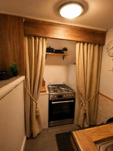 a kitchen with a stove and a window with curtains at Suite spa Romantique avec piscine privée cosy clim in Coligny