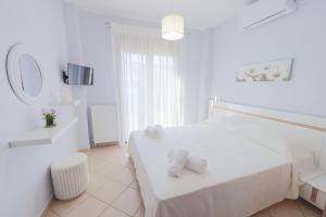 a white bedroom with a bed with towels on it at Electras house in Kassandra
