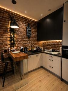 a kitchen with white cabinets and a brick wall at Brick Loft Nikiszowiec in Katowice