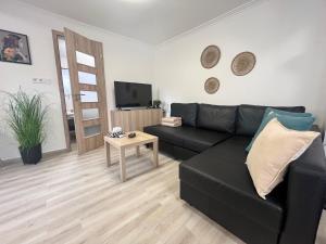 a living room with a black couch and a table at Kincsem Vendégház in Tiszakécske