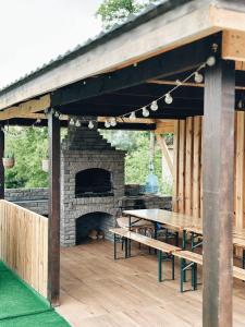 a picnic table and a fireplace in a pavilion at Зелена долина in Solgutovo
