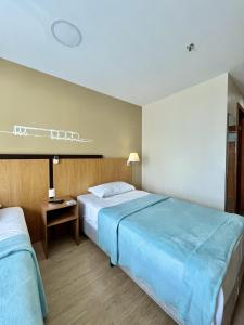 a hotel room with two beds and a table at Flat 609 - Comfort Hotel Taguatinga - Particular in Brasília +16 photos