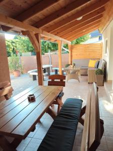 a patio with a wooden table and benches at Kincsem Vendégház in Tiszakécske