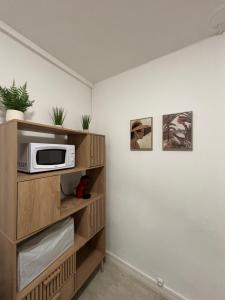 a kitchen with a microwave on a wooden shelf at Studio cosy proche transports in Aulnay-sous-Bois