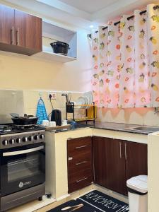 a small kitchen with a stove and a curtain at SerenityLoft by Gloria in Thika