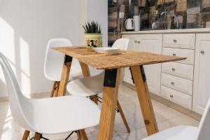 a kitchen with a wooden table and white chairs at Petit house Vrachati in Vrachati