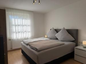 a bedroom with a bed with white sheets and a window at Seegarten Apartment 4 in Hagnau +10 photos