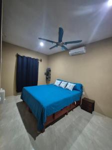 ein Schlafzimmer mit einem blauen Bett und einem Deckenventilator in der Unterkunft Casa Haema in El Cuyo