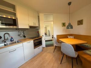 a kitchen with white cabinets and a wooden table at Seegarten Apartment 4 in Hagnau