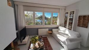 a living room with a white couch and a tv at Villa Jordana Urbapol One Step To The Beach in San Pol de Mar