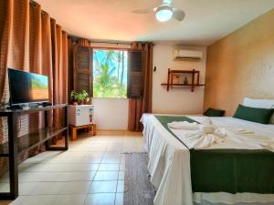 a bedroom with a bed and a television and a window at Casa Mandacaru Pousada in Cumbuco