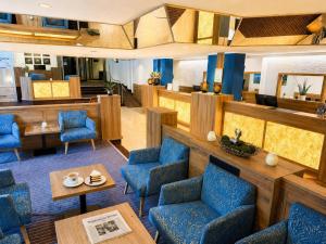 a waiting room with blue chairs and tables at AMBER HOTEL Bavaria in Bad Reichenhall
