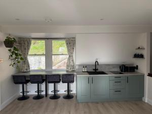 a kitchen with a sink and a counter with stools at Courtyard Apartament in Ballymore