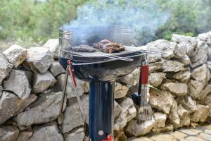 a grill with meat on top of a stone wall at House Lila Jacuzzy in Drvenik Mali